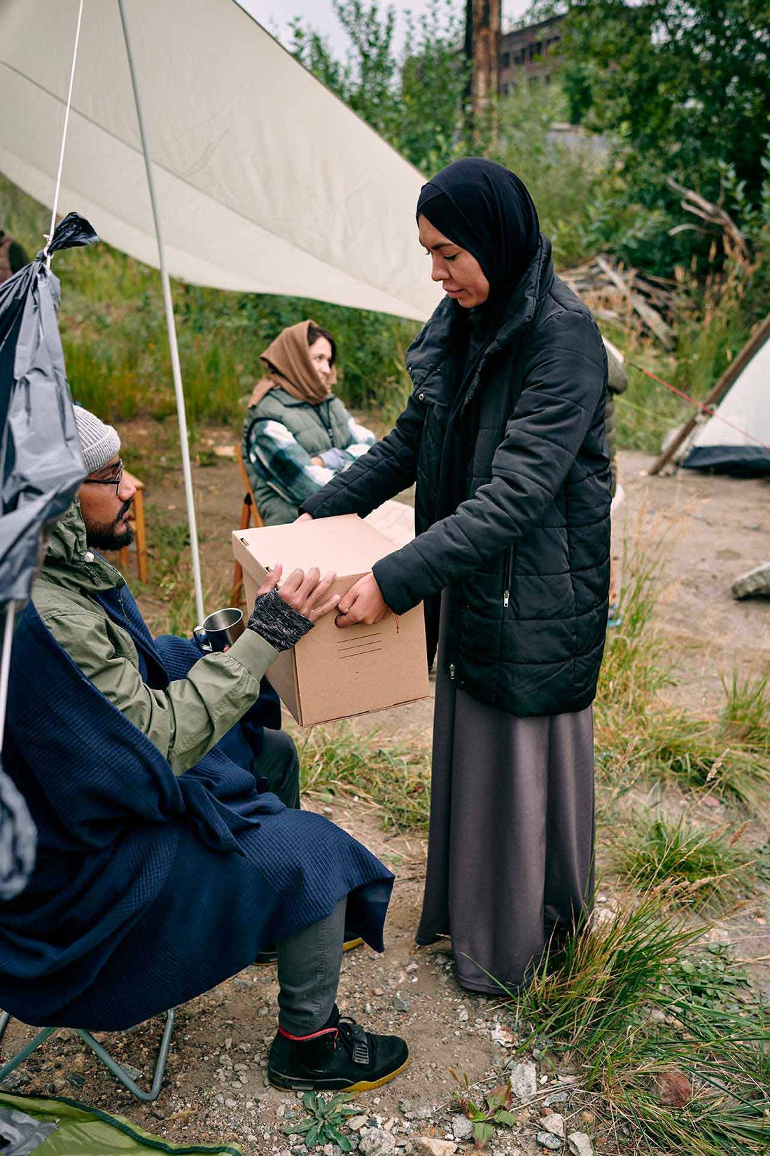 A volunteer handing a box of supplies to a family outdoors