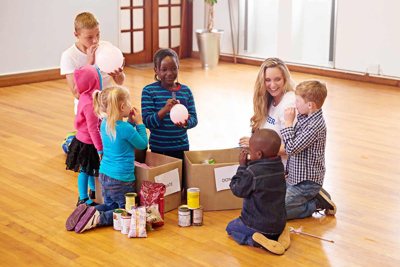 A volunteer unpacking donation boxes with a group of children